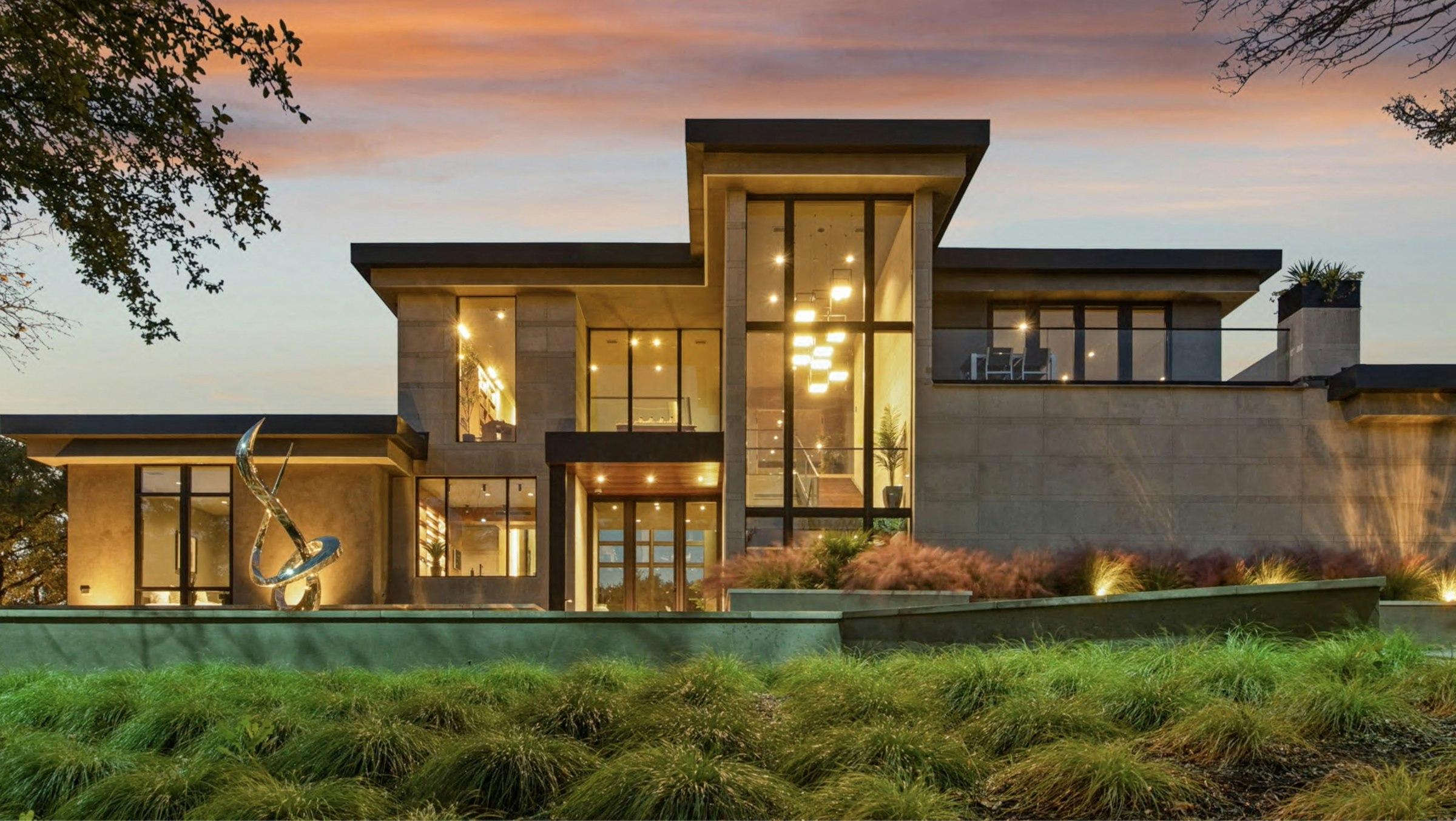 Modern luxury home at dusk with warm interior lighting